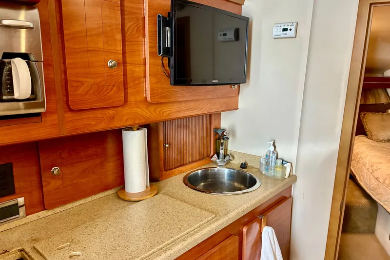Slide: The Image of 2006 Rinker 390 Express Cruiser interior with kitchenette, sink, TV, and cozy cabin view. - 29