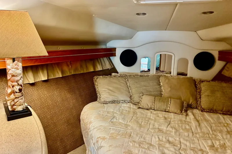 Slide: The Image of Cozy cabin interior of 2006 Rinker 390 Express Cruiser with plush bedding and decorative lamp. - 36