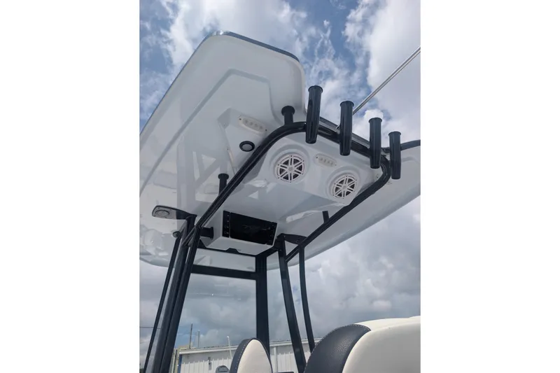 Slide: The Image of Tidewater 2300 Carolina Bay 2026 boat T-top with rod holders and speakers under cloudy sky. - 7