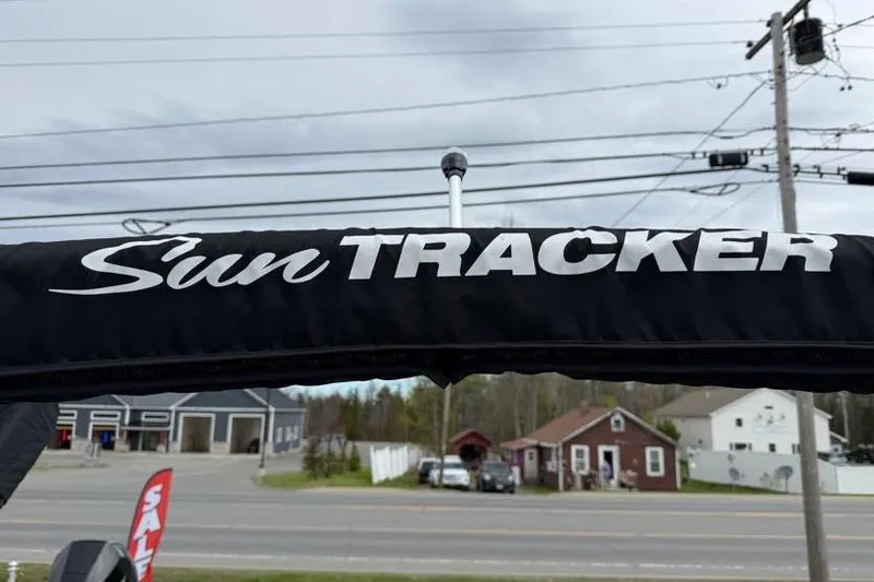 Slide: The Image of Sun Tracker Party Barge 16 DLX 2025 canopy with logo, roadside view. - 43