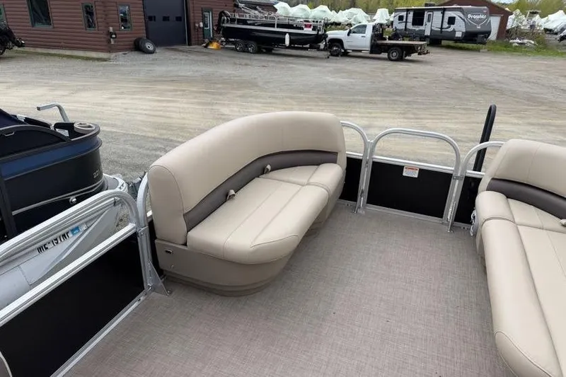 Slide: The Image of 2025 Sun Tracker Party Barge 16 DLX interior with beige seating, parked outdoors. - 49