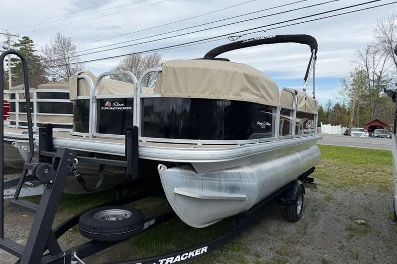 Slide: The Image of 2025 Sun Tracker Party Barge 16 DLX pontoon boat on trailer, covered and parked outdoors. - 56