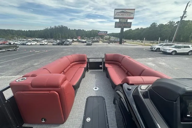 Slide: The Image of 2026 Regency 230 DL pontoon boat with red seating, parked in a dealership lot. - 10