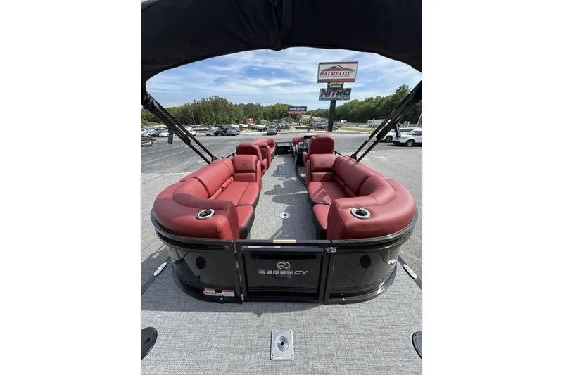 Slide: The Image of 2026 Regency 230 DL pontoon boat with red seating and canopy, parked outdoors. - 6