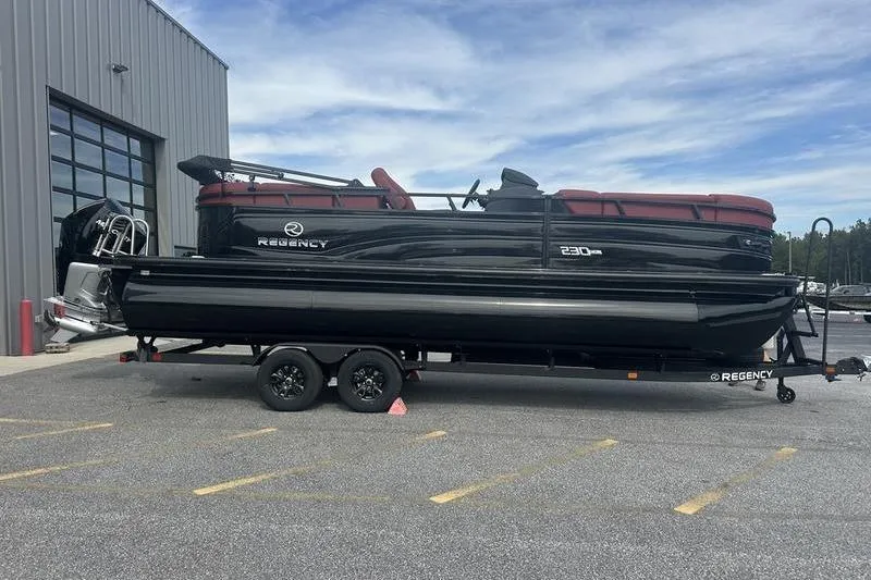 Slide: The Image of 2026 Regency 230 DL pontoon boat on trailer, parked outside a building. - 9