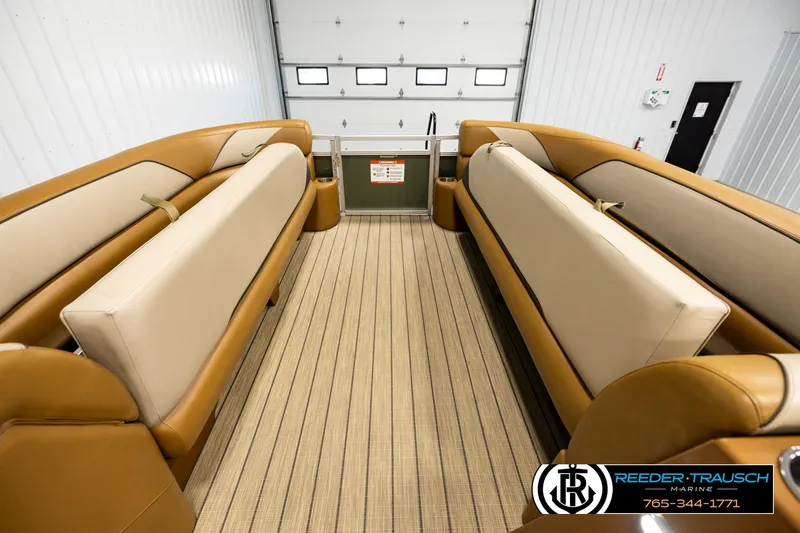 Slide: The Image of 2023 Avalon VEN CR boat interior with tan seating and striped flooring in a showroom. - 19