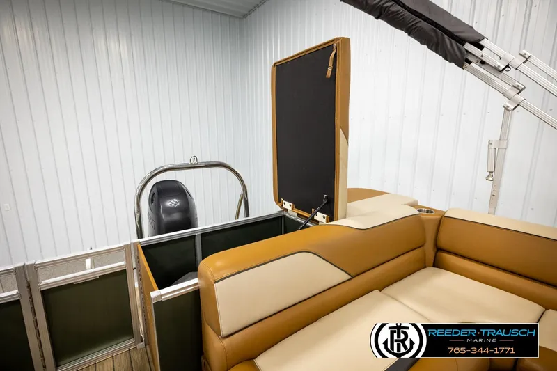 Slide: The Image of 2023 Avalon VEN CR boat interior with tan seating and motor, displayed indoors. - 24