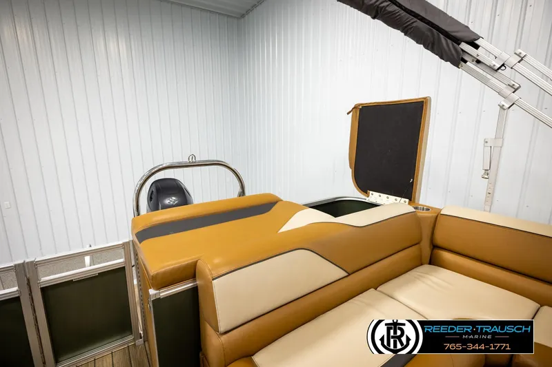 Slide: The Image of 2023 Avalon VEN CR boat interior with tan seating and motor, in a storage facility. - 25