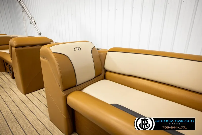 Slide: The Image of 2023 Avalon VEN CR boat interior with tan and cream seating, Reeder-Trausch Marine logo. - 28
