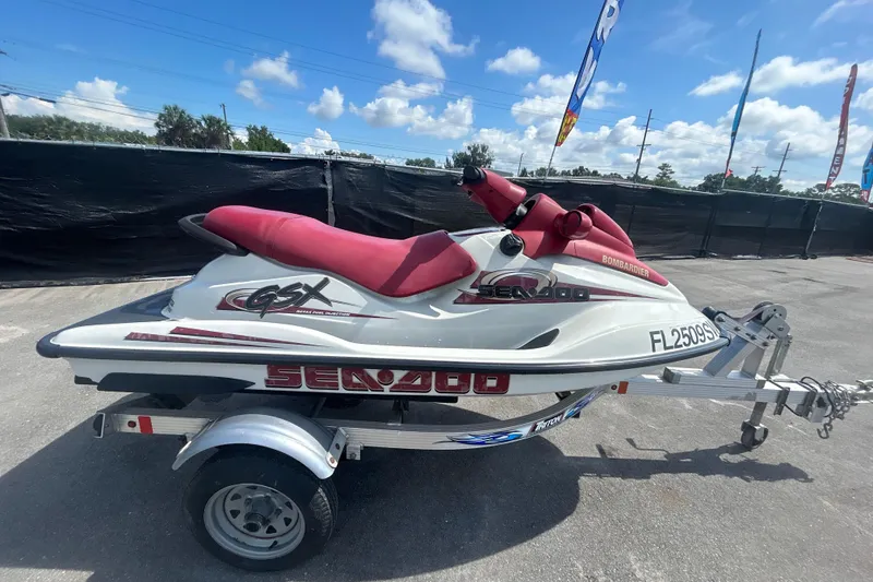 Slide: The Image of 1999 Sea Doo Jet Ski on trailer, red and white design, parked outdoors. - 2