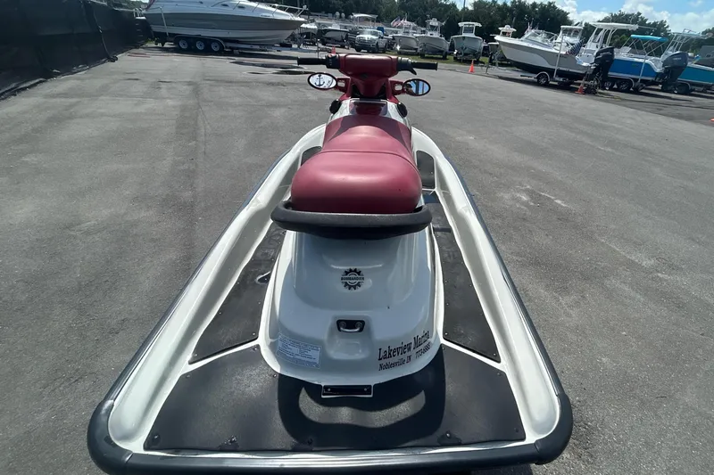 Slide: The Image of 1999 Sea Doo Jet Ski with red seat, parked in a marina with boats in background. - 4