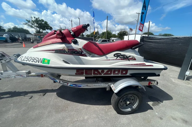 Slide: The Image of 1999 Sea Doo Jet Ski on trailer, red and white, parked outdoors under blue sky. - 7