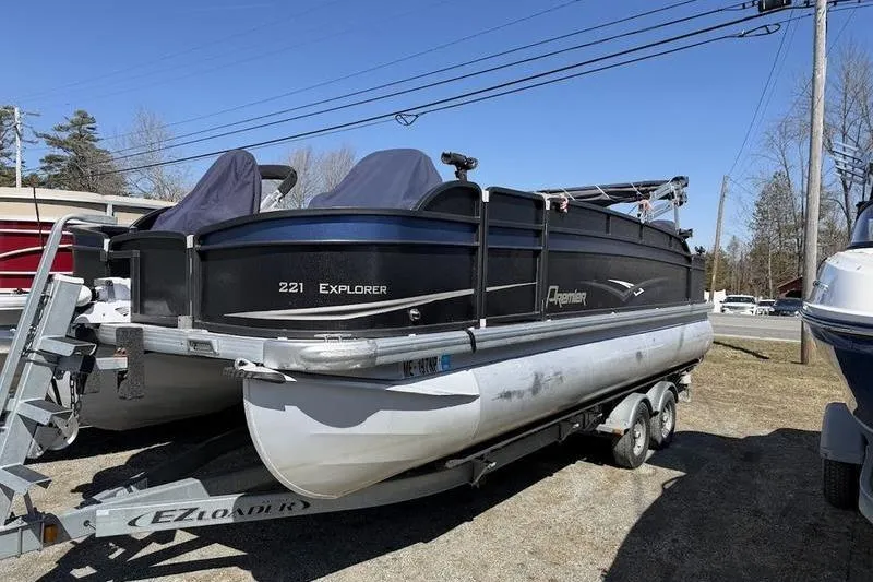 The Image of 2013 Premier 221 Explorer pontoon boat on trailer, parked outdoors under clear blue sky. - 0