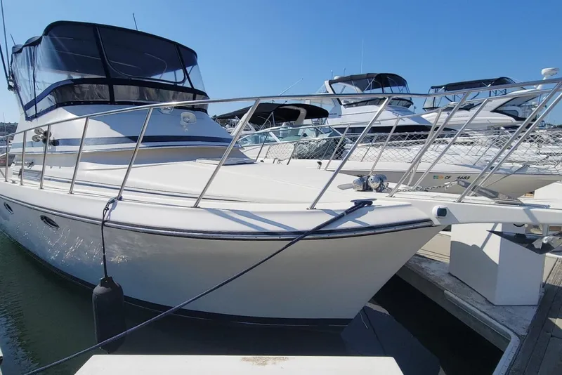 The Image of 1989 Navigator 34 Flybridge yacht docked at marina under clear blue sky. - 0