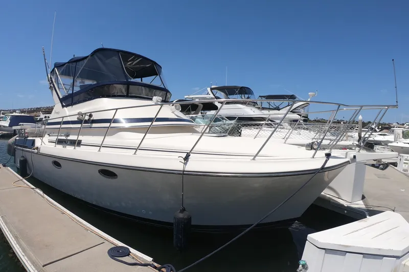 Slide: The Image of 1989 Navigator 34 Flybridge yacht docked at marina under clear blue sky. - 1