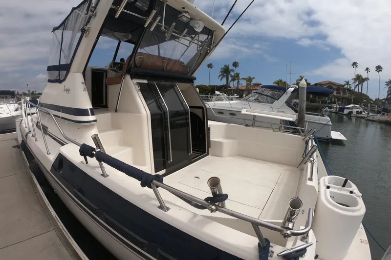 Slide: The Image of 1989 Navigator 34 Flybridge yacht docked at marina, featuring spacious deck and sleek design. - 2