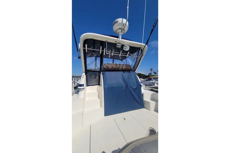 Slide: The Image of 1989 Navigator 34 Flybridge yacht with blue canopy, docked under clear sky. - 3