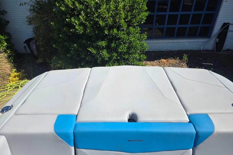 Slide: The Image of 2022 MasterCraft NXT24 boat with blue and white upholstery, parked outdoors. - 11