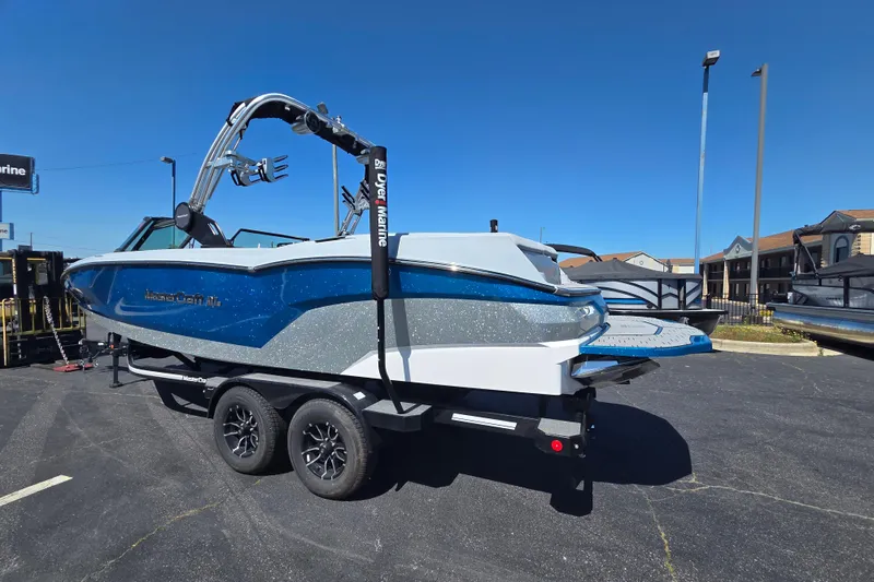 Slide: The Image of 2022 MasterCraft NXT24 boat on trailer, blue and white design, parked outdoors. - 3