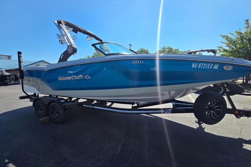 Slide: The Image of 2022 MasterCraft NXT24 boat on trailer, blue and white, parked outdoors. - 4