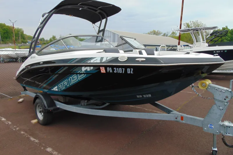 The Image of 2021 Yamaha Boats AR195 on trailer, sleek black design, parked outdoors. - 1