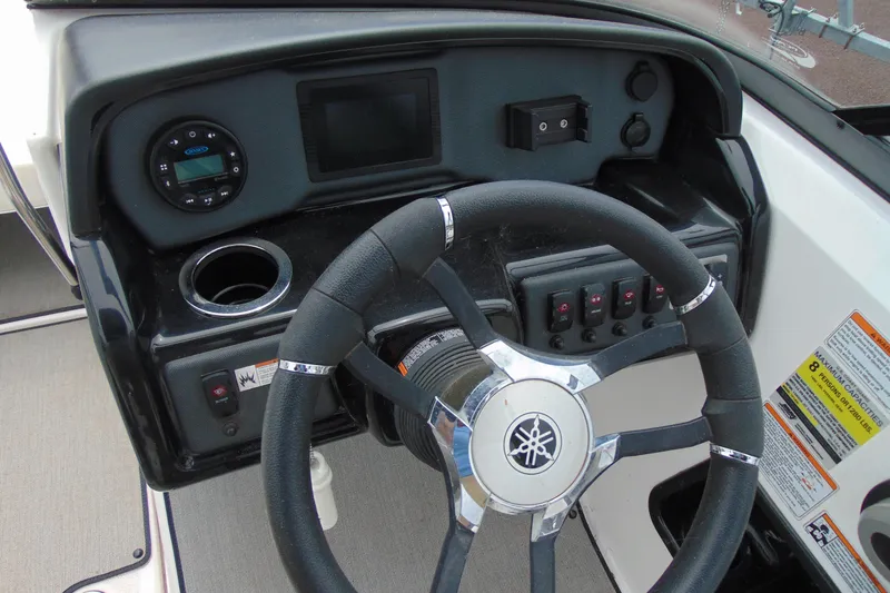 Slide: The Image of Steering wheel and dashboard of 2021 Yamaha Boats AR195, featuring controls and cup holder. - 10