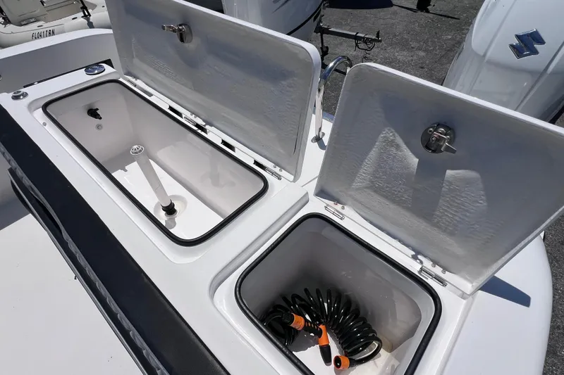Slide: The Image of 2023 Twin Vee 240 GFX CC boat storage compartments with open lids and coiled hose. - 16
