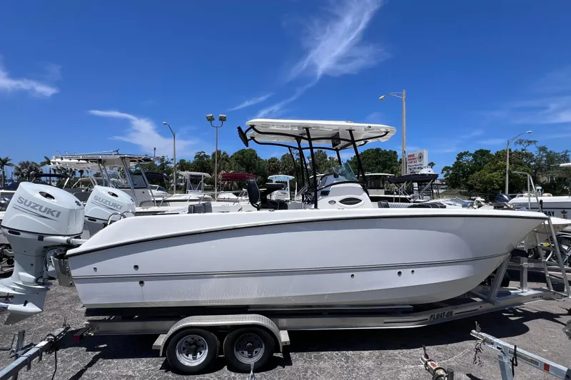 Slide: The Image of 2023 Twin Vee 240 GFX CC boat on trailer with Suzuki engines, under clear blue sky. - 2