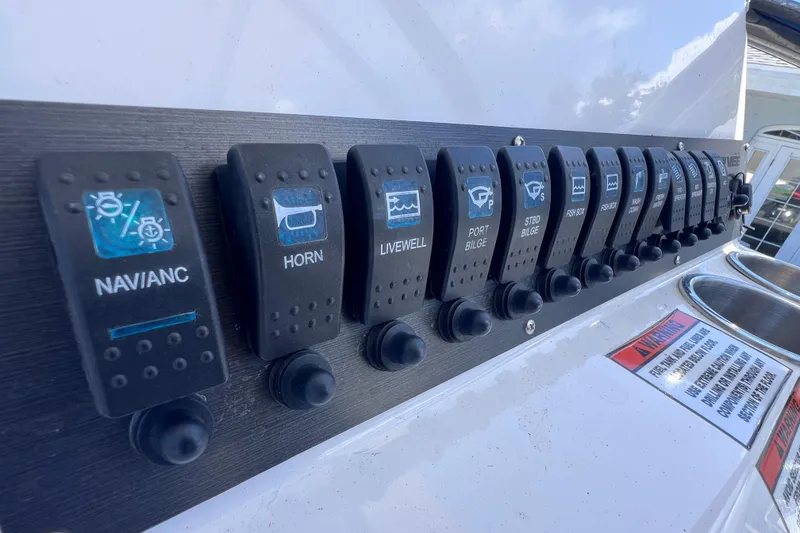 Slide: The Image of Control panel of 2023 Twin Vee 240 GFX CC boat with labeled switches. - 24