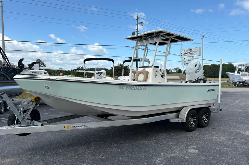 The Image of 2021 Sundance DX22 boat on trailer, parked outdoors under blue sky. - 0
