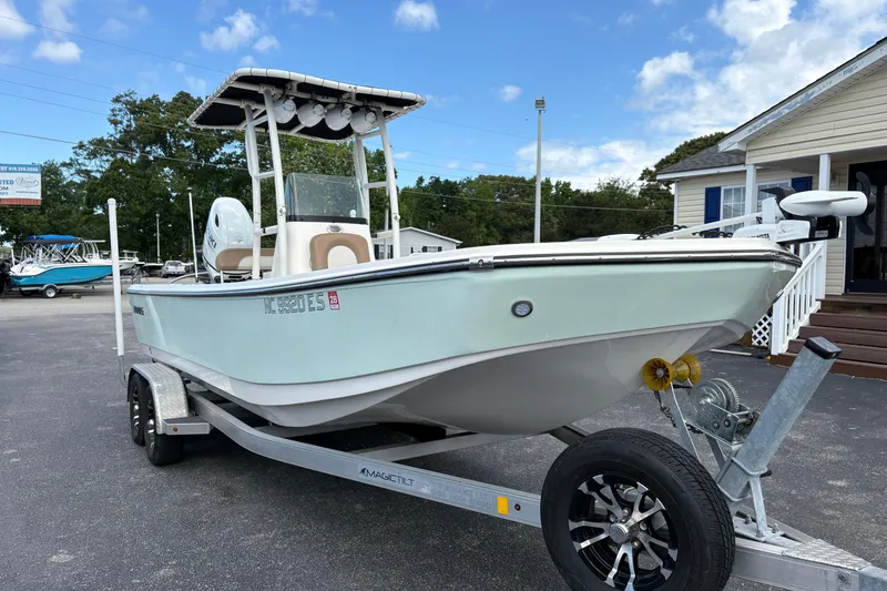 Slide: The Image of 2021 Sundance DX22 boat on trailer, parked outdoors under a partly cloudy sky. - 4