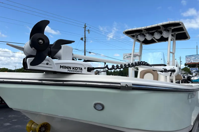 Slide: The Image of 2021 Sundance DX22 boat with Minn Kota PowerDrive motor, parked outdoors under blue sky. - 5