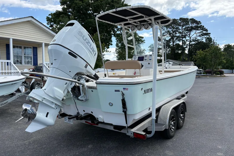 Slide: The Image of 2021 Sundance DX22 boat with Suzuki outboard motor on a trailer, parked outdoors. - 6