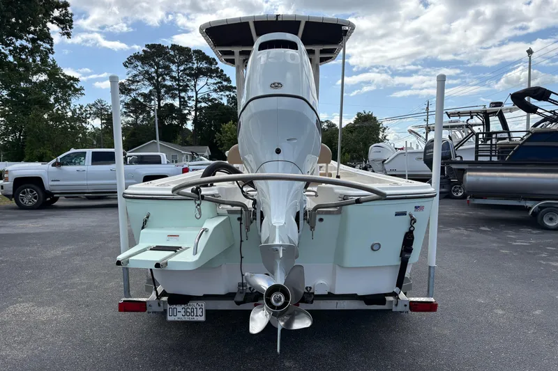 Slide: The Image of Sundance DX22 boat, 2021 model, parked with outboard motor, surrounded by vehicles. - 7
