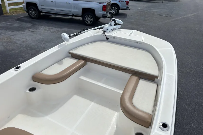 Slide: The Image of 2021 Sundance DX22 boat interior with seating and trolling motor in parking lot. - 9
