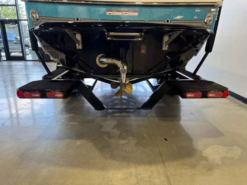 Slide: The Image of The image shows the rear of a 2026 Nautique Super Air Nautique GS22 boat in a showroom. - 7
