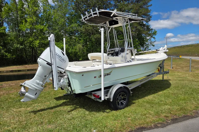 Slide: The Image of 2022 Bulls Bay 2000 boat on trailer with Suzuki outboard motor, parked on grass. - 2