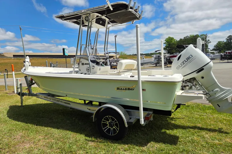 Slide: The Image of 2022 Bulls Bay 2000 boat with Suzuki outboard motor on a trailer, parked on grass. - 5