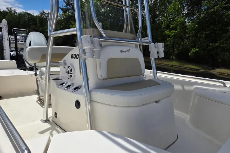 Slide: The Image of 2022 Bulls Bay 2000 boat interior with seating and rod holders, surrounded by lush greenery. - 9