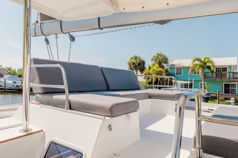Slide: The Image of 2020 Fountaine Pajot Saona 47 catamaran deck with cushioned seating, docked near waterfront homes. - 22