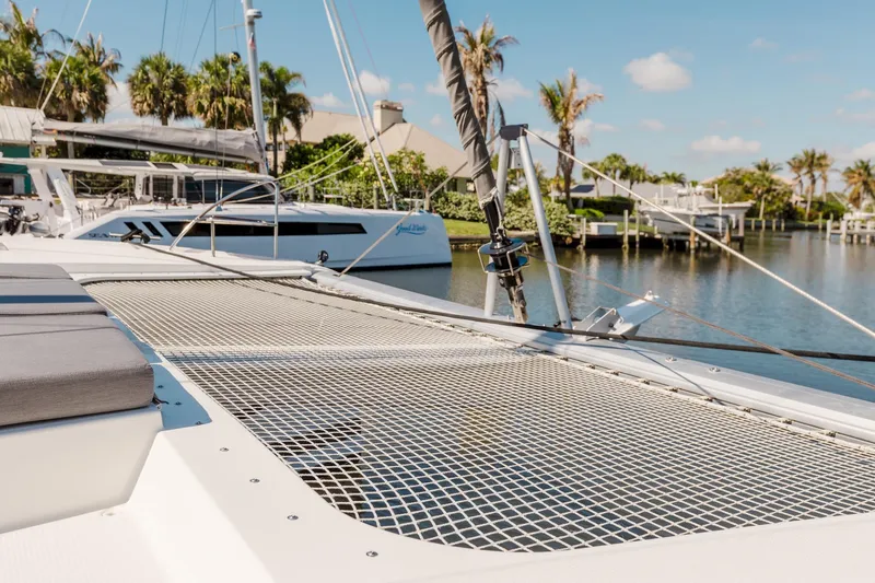 Slide: The Image of 2020 Fountaine Pajot Saona 47 catamaran docked by palm trees and waterfront homes. - 25