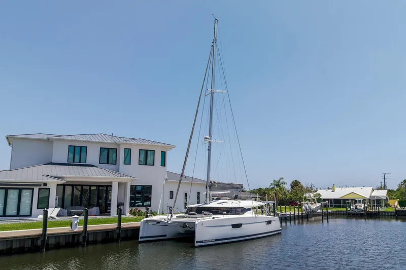 Slide: The Image of 2020 Fountaine Pajot Saona 47 catamaran docked by a modern waterfront home. - 68