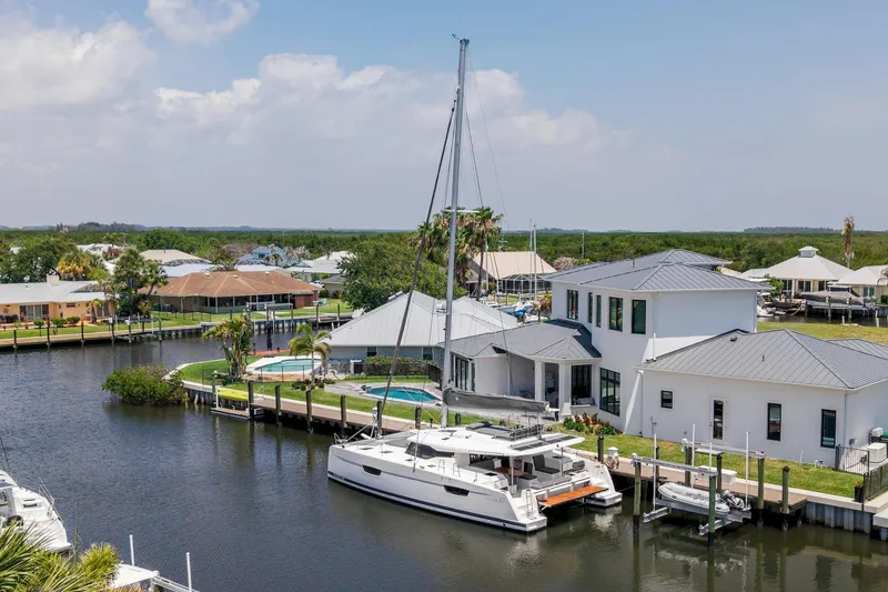 Slide: The Image of 2020 Fountaine Pajot Saona 47 catamaran docked by waterfront homes under a clear sky. - 69