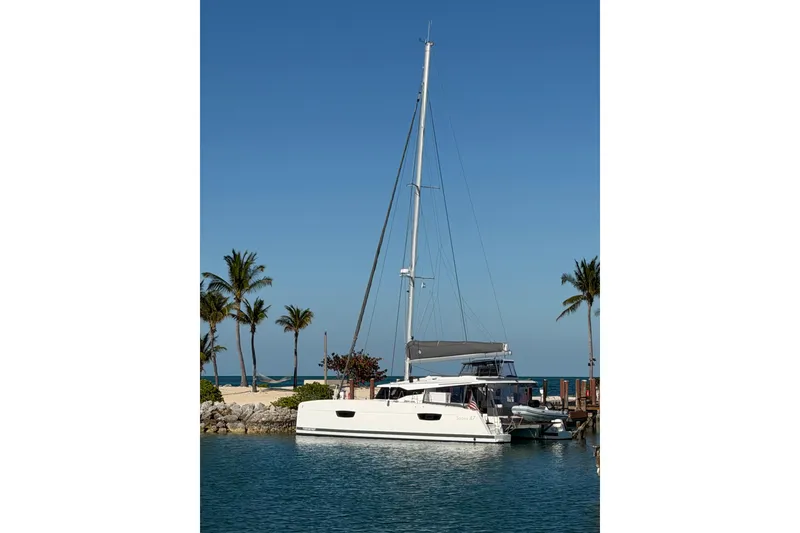Slide: The Image of 2020 Fountaine Pajot Saona 47 catamaran docked by palm trees under clear blue sky. - 79