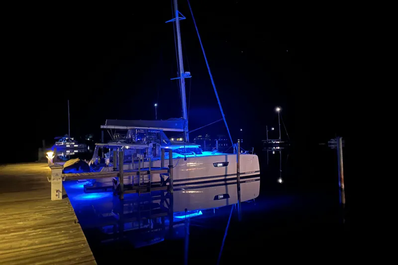 Slide: The Image of Night view of a 2020 Fountaine Pajot Saona 47 catamaran with blue lights at a dock. - 88