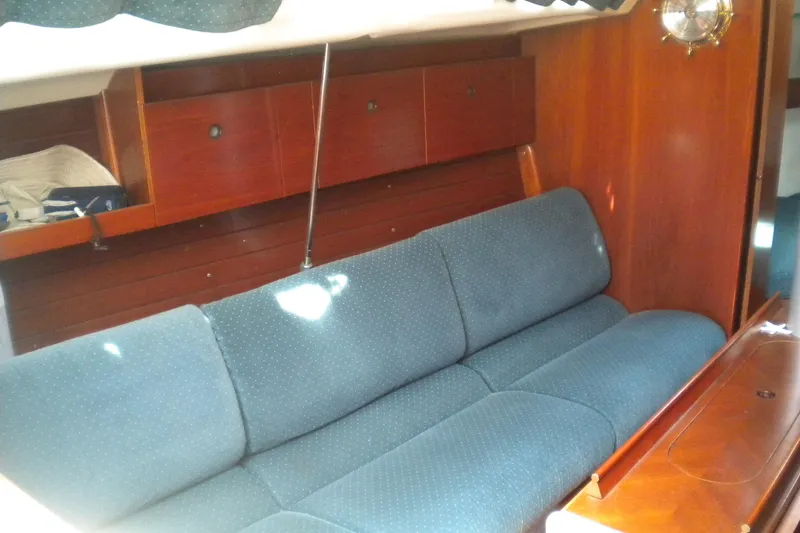 Slide: The Image of Interior of a 1994 Beneteau First 310 sailboat with blue sofa and wooden cabinets. - 11