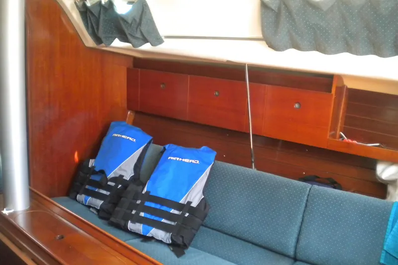 Slide: The Image of Interior of 1994 Beneteau First 310 sailboat with blue life jackets on a cushioned bench. - 12