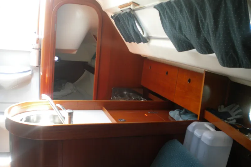 Slide: The Image of Interior of 1994 Beneteau First 310 sailboat with wooden cabinetry and compact kitchen area. - 14