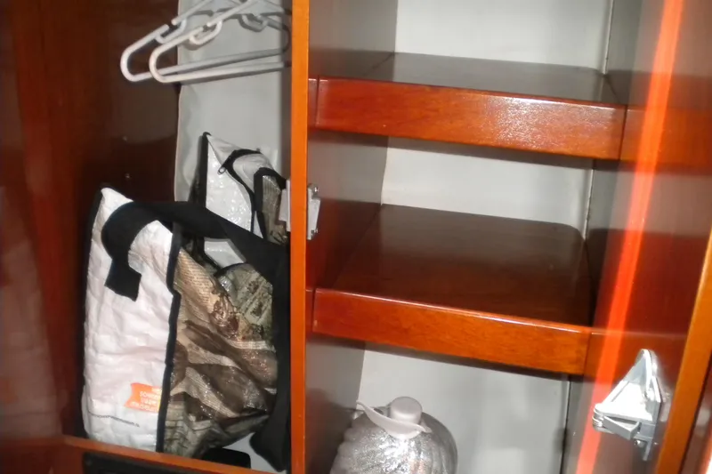 Slide: The Image of Wooden cabinet interior on a 1994 Beneteau First 310 sailboat, featuring shelves and storage bags. - 17
