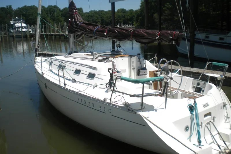 Slide: The Image of 1994 Beneteau First 310 sailboat docked in a marina, showcasing sleek design and white hull. - 2